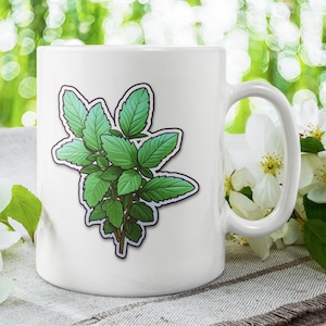 Peut inclure: Une tasse en céramique blanche avec une illustration d'une plante de menthe verte sur le devant. La tasse est posée sur une surface brun clair avec des fleurs blanches en arrière-plan.