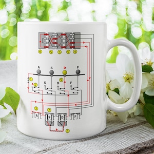 May include: White ceramic mug featuring a black and red electrical diagram printed on it. The diagram depicts a series of switches and wires labelled with letters and numbers.