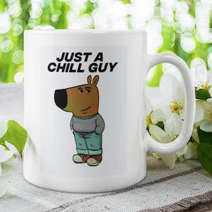 Könnte beinhalten: Weiße Keramik-Tasse mit einer Cartoon-Illustration eines hundeartigen Charakters in grauem Pullover, blauer Jeans und roten Schuhen. Der Becher trägt den schwarzen Text "JUST A CHILL GUY". Im Hintergrund weiße Blüten und grünes Laub.