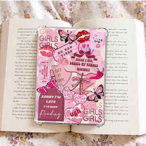 May include: Pink and white phone case with various stickers, including "Girls Girls Girls", "No Bad Vibes", "When I Die, Delete My Kindle History", "Get It Girl", "Sorry I'm Late I've Been Reading", and "Ugh".