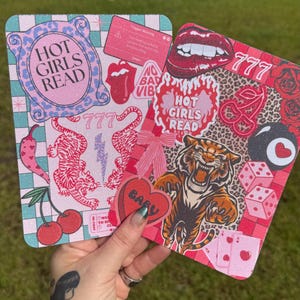 Puede incluir: Dos posavasos decorativos con diseños vibrantes. Uno presenta un fondo rosa con tigres, cerezas y el texto "HOT GIRLS READ". El otro tiene estampado de leopardo, labios, dados y un tigre. Ambos tienen el número "777".