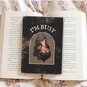 Könnte beinhalten: Eine Schwarzweißillustration einer Frau mit langen schwarzen Haaren, die ein Buch liest. Der Text "I'M BUSY" ist in weißen Buchstaben auf schwarzem Hintergrund geschrieben.
