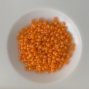 Cousin beads and iridescent tangerine company. Small French glass beads. About 500 per bag.