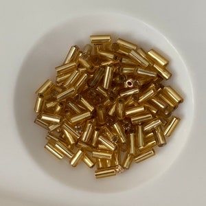 Cousin beads and long transparent gold company. Small French glass beads. Approximately 150/200 beads per bag.