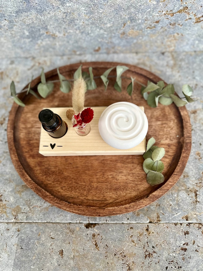 Duftspirale auf Holzbrett, daneben ein Reagenzglas mit Blumen und ein Loch für Duftöl