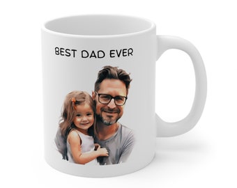 Puede incluir: Taza de cerámica blanca con la inscripción en negro "BEST DAD EVER" y una foto de un padre y su hija. El padre lleva gafas y una camisa gris. La hija lleva un vestido blanco y tiene los brazos alrededor del cuello de su padre.