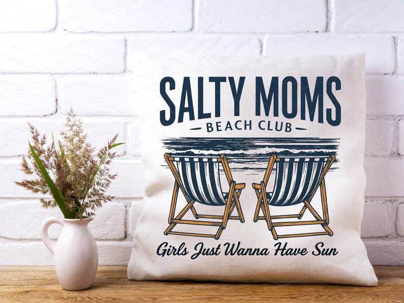 May include: White cushion with the text "Salty Moms Beach Club" and an illustration of two deckchairs with the text "Girls Just Wanna Have Sun" below.
