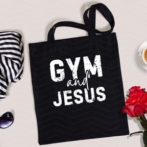 May include: Black canvas tote bag with white text that reads "GYM and JESUS".