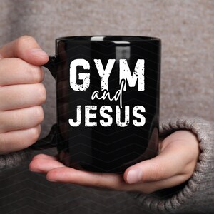 May include: Black coffee mug with white text that reads "GYM and JESUS".