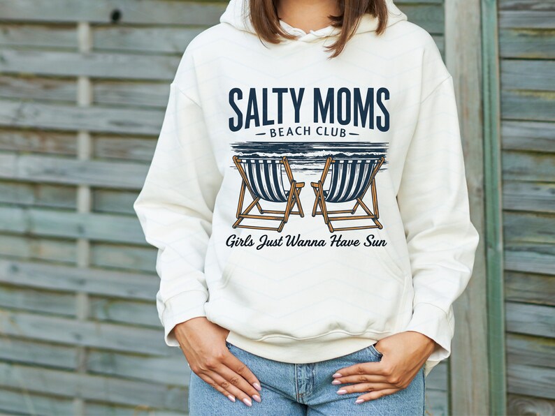 May include: A white hoodie with a graphic design that says "Salty Moms Beach Club" with two beach chairs and the text "Girls Just Wanna Have Sun".