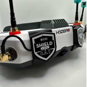 May include: A white and black HDZERO FPV drone with two black antennas and a black Micro Shield 5.8GHz O.R.T. sticker on the front. The drone has a black and gray HDZERO logo on the side.