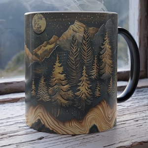 Puede incluir: Una taza de cerámica negra con un diseño de escena de montaña y bosque. La taza tiene un asa negra y está llena de una bebida humeante. La escena presenta una luna llena, montañas y árboles en tonos dorados y marrones.