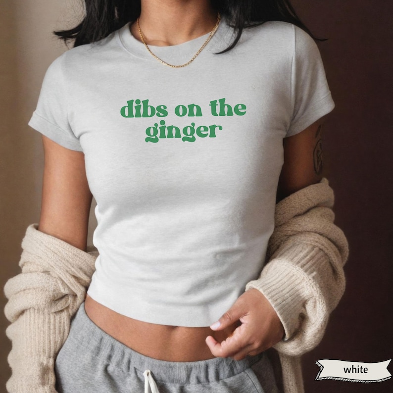 以下が含まれることがあります： 緑色の文字で「dibs on the ginger」と書かれた白いTシャツです。