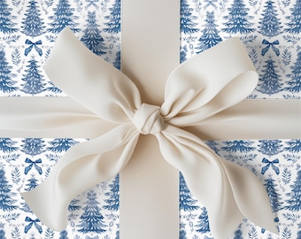 May include: A gift wrapped in white paper featuring a repeating blue watercolor pattern of Christmas trees, bows, and sprigs. A wide, smooth, cream-colored satin ribbon is tied in a large, centered bow across the front of the package.