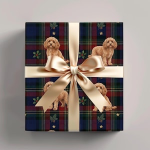 Könnte beinhalten: Ein quadratisches Geschenkpaket in dunkelblauem, rotem und grünem Schottenkaro-Papier mit einem Muster aus hellbraunen, lockigen Hunden, Stechpalmenzweigen und kleinen goldenen Sternen, gebunden mit einem breiten, glatten champagnerfarbenen Satinband.