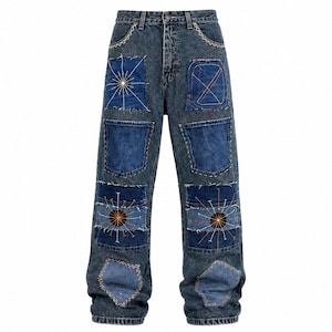 Peut inclure: Jean en denim bleu foncé avec un design en patchwork composé de divers empiècements rectangulaires et irréguliers. Le pantalon présente des motifs de rayons de soleil brodés, des coutures blanches visibles et des bords effilochés sur les pièces.
