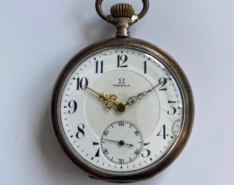 Reloj de bolsillo antiguo Omega plateado con esfera abierta.