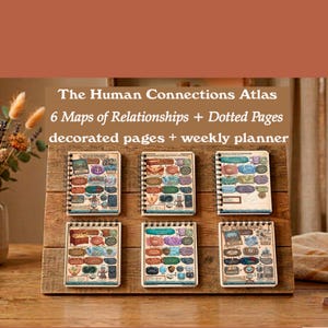 Puede incluir: Seis cuadernos con espiral con diseños de mapas coloridos se exhiben en un soporte de madera. Los cuadernos están etiquetados como "The Human Connections Atlas" e incluyen "6 Maps of Relationships + Dotted Pages decorated pages + weekly planner."