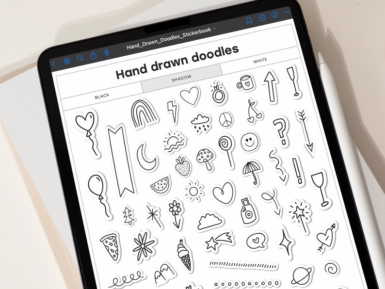 Pode incluir: A tela de um tablet digital mostra uma folha de adesivos com rabiscos desenhados &agrave; m&atilde;o em preto e branco. Os rabiscos incluem um cora&ccedil;&atilde;o, um arco-&iacute;ris, um raio, uma nuvem, um sinal de paz, uma pirulito, um cogumelo, um guarda-chuva, uma estrela, uma flor, uma fatia de pizza, uma onda, uma montanha, uma estrela cadente, um bal&atilde;o de fala, um planeta e um c&iacute;rculo. O texto na tela diz "Hand drawn doodles" e "Hand_Drawn_Doodles_Stickerbook".
