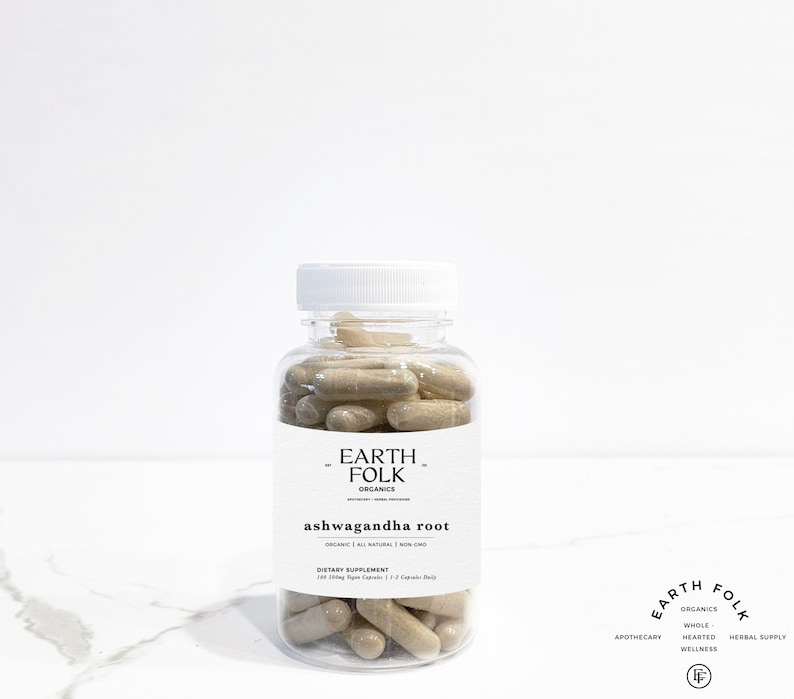 May include: A clear plastic bottle filled with beige capsules labeled "Earth Folk Organics Ashwagandha Root" with the text "Organic | All Natural | Non GMO" and "Dietary Supplement 120 500mg Vegan Capsules | 2 Capsules Daily".