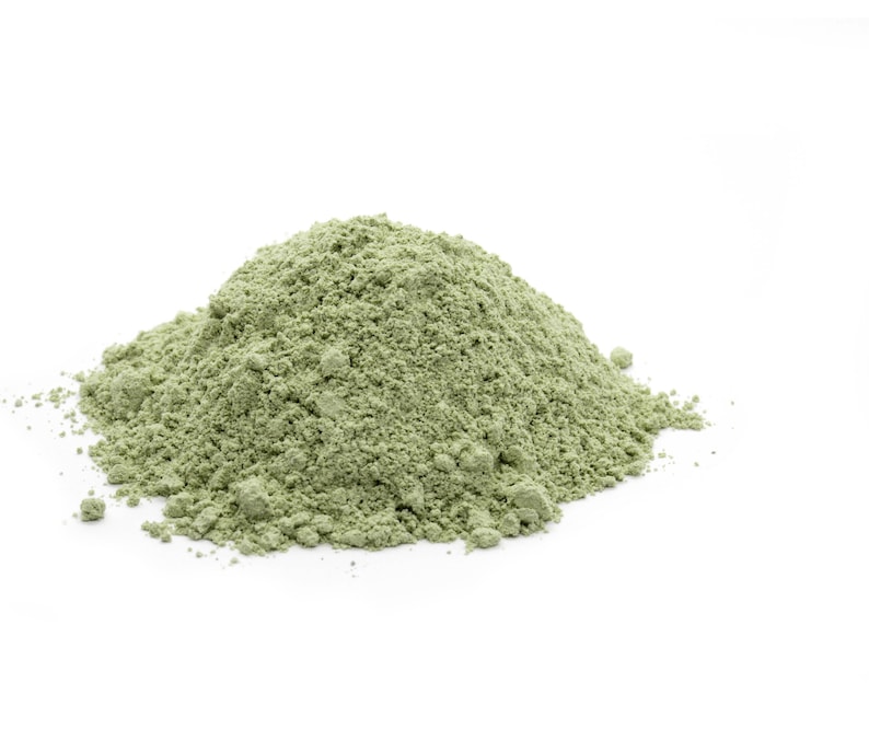 May include: A pile of light green powder on a white background.