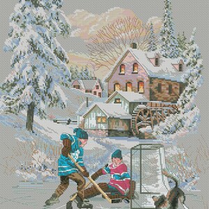 May include: Two children play hockey on a frozen pond in front of a snowy village. The child in blue is skating towards the goal while the child in red is sitting on the ice. A dog is watching the game.