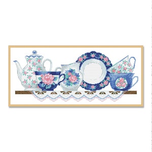 Peut inclure: Un ensemble de tasses à thé et d'une théière bleu et blanc avec des motifs floraux roses, disposés sur une étagère avec une dentelle.