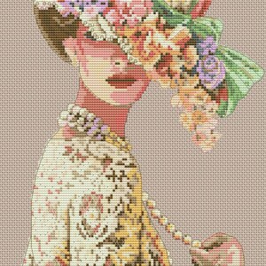 May include: A woman wearing a white dress with a floral pattern and a large hat adorned with pink, green, and purple flowers. She is holding a string of pearls in her hand.