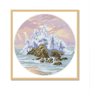 May include: A cross-stitch embroidery showing a group of white horses standing on a rocky island in the sea. The horses are surrounded by waves and the sky is a soft pink and purple.