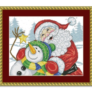 May include: Santa Claus in a red suit with a white beard and hat is hugging a snowman wearing a green hat and a yellow and blue scarf. The snowman has a carrot nose and black eyes. The background is a snowy winter scene with trees.