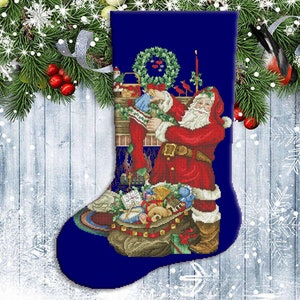 Puede incluir: Una media navideña azul con una figura de Papá Noel llenándola de regalos. La media está decorada con una corona, una chimenea y otros detalles festivos.