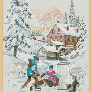 May include: Two children wearing hockey jerseys play hockey on a frozen pond in front of a snowy village. A dog watches them play.