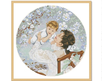 May include: A mother and child in a white dress and white onesie, respectively, are sitting in a garden setting. The mother is holding the child in her arms, and they are both looking at each other. The background is a blurred image of flowers and greenery.