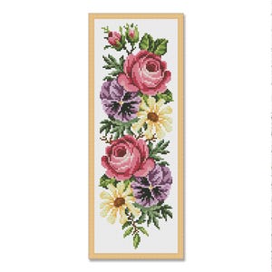 May include: A cross-stitch floral design featuring pink roses, purple pansies, and yellow daisies. The flowers are arranged vertically within a rectangular frame. Green leaves and buds add detail to the floral arrangement.