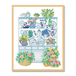 Könnte beinhalten: Ein blaues und weißes Porzellanschrank mit drei Regalen, gefüllt mit Teetassen, Teekannen und anderen Dekorationsartikeln. Der Schrank ist mit Blumen verziert und hat einen Holzrahmen.