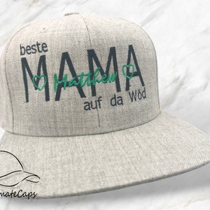 Könnte beinhalten: Eine graue und weiße Baseballkappe mit dem Text "beste MAMA Matthew auf da Wöd" in Schwarz und Grün gestickt.