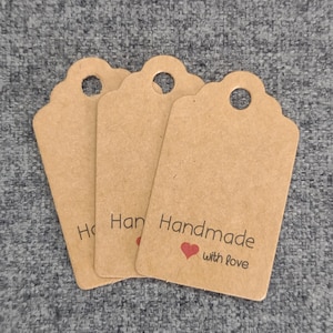 May include: Three brown paper gift tags with scalloped edges and a hole at the top. The tag on the right has the text "Handmade with love" and a red heart.