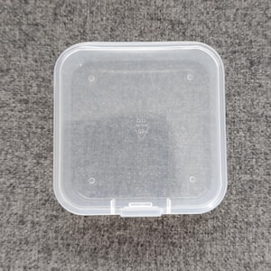 May include: A clear plastic square storage container with a hinged lid. The container has a small label on the bottom that reads "6D 024".