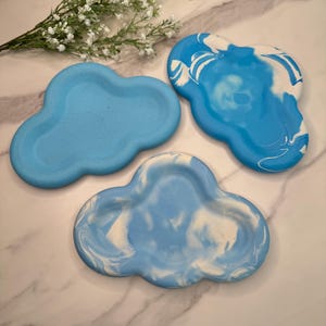 May include: Three blue and white cloud-shaped ceramic trays. Two of the trays have a marbled design, and one is solid blue.