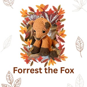 May include: A crocheted fox toy with orange and brown yarn, sitting amidst autumn leaves. The fox has dark brown paws and a white-tipped tail. The text "Forrest the Fox" is displayed below the fox.