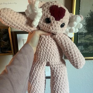 May include: A set of three ceramic mugs with a speckled, cream-colored glaze. Each mug features a different hand-painted design: a blue and green leaf, a yellow flower, and a red berry. The mugs have a simple, rounded shape.