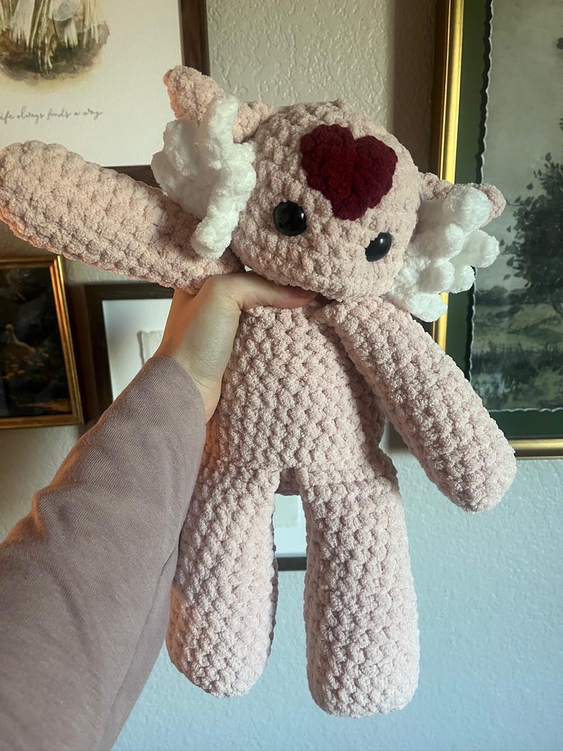 May include: A set of three ceramic mugs with a speckled, cream-colored glaze. Each mug features a different hand-painted design: a blue and green leaf, a yellow flower, and a red berry. The mugs have a simple, rounded shape.