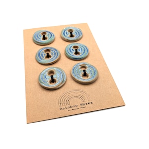 Puede incluir: Un juego de tres tazas de cerámica con acabado mate moteado. Las tazas son de color crema, gris claro y gris oscuro. Cada taza tiene un diseño simple y minimalista.