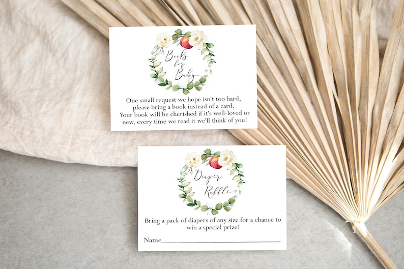 May include: Two white cards with floral wreaths and text. The top card says "Books for Baby" and asks guests to bring a book instead of a card. The bottom card says "Diaper Raffle" and asks guests to bring a pack of diapers for a chance to win a prize.