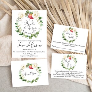 May include: A set of three white cards with watercolor illustrations of a peach and floral wreath. The text on the cards reads "The apple of my eye is on the way!"  "Please join us for a baby shower honoring Lori Johnson", "Diaper Raffle", and "Books for Baby".