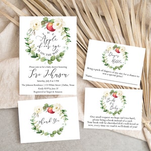 May include: A set of three white cards with watercolor illustrations of a peach and floral wreath. The text on the cards reads "The apple of my eye is on the way!"  "Please join us for a baby shower honoring Lori Johnson", "Diaper Raffle", and "Books for Baby".