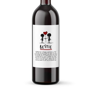 May include: A bottle of red wine with a white label that says "Bestie" and features a cartoon drawing of two stick figures holding a red heart balloon. The label also includes a short message about friendship.