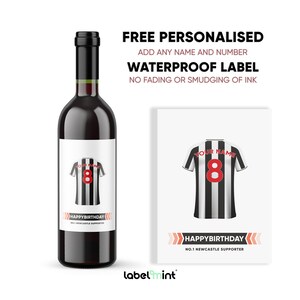 May include: A personalized wine bottle label with a black and white football jersey design. The label features the text "Happy Birthday" and "No. 1 Newcastle Supporter".