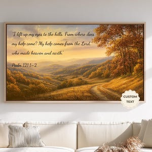 May include: A rectangular landscape wall art print in a light wood frame featuring a golden sunset over rolling hills and autumn trees. The text reads: I lift up my eyes to the hills. From where does my help come? My help comes from the Lord, who made heaven and earth. Psalm 121:1-2.