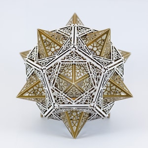 Può includere: Una scultura geometrica dorata e bianca con un design a forma di stella. La scultura è realizzata con pezzi intricati, tagliati al laser, che creano un motivo delicato e intricato.
